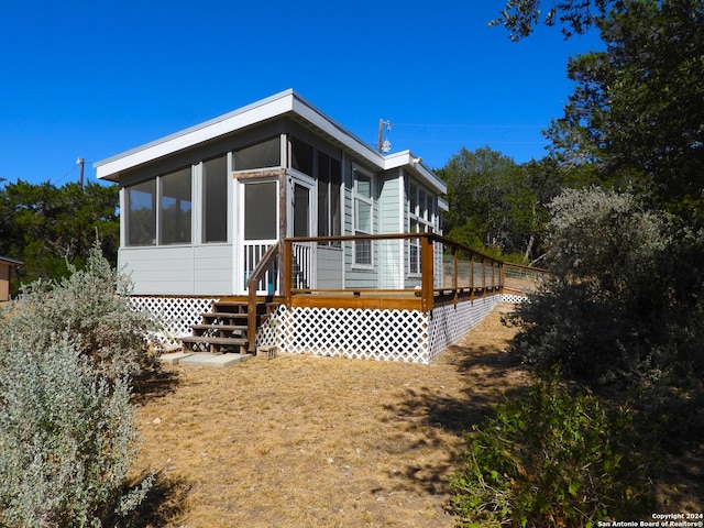 rear view of house with a wooden deck and a sunroom