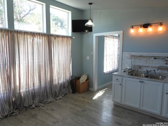 kitchen featuring sink, white cabinetry, pendant lighting, decorative backsplash, and light hardwood / wood-style flooring