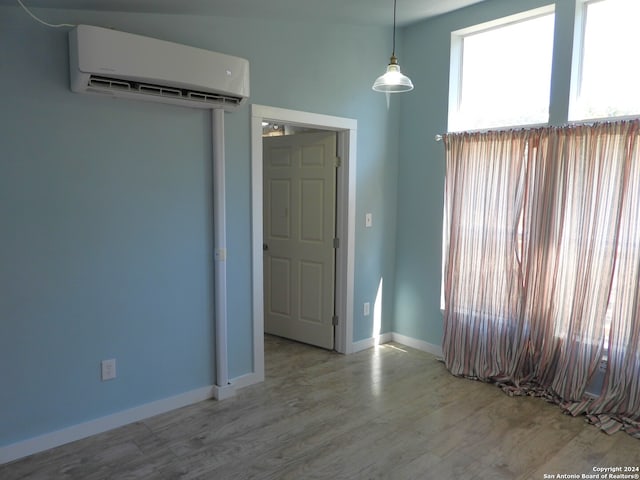 unfurnished room with an AC wall unit and light wood-type flooring