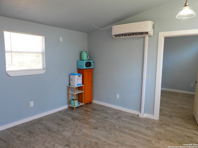 interior space with light hardwood / wood-style floors, lofted ceiling, and an AC wall unit