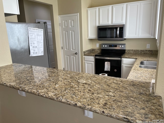 kitchen featuring light stone counters, appliances with stainless steel finishes, kitchen peninsula, and white cabinetry