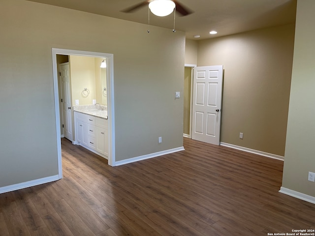 unfurnished bedroom featuring ensuite bathroom, sink, dark wood-type flooring, and ceiling fan