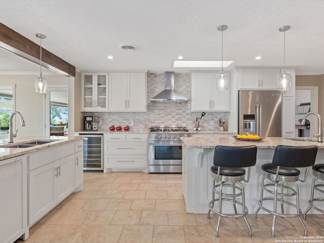 kitchen with high end appliances, white cabinets, beverage cooler, and wall chimney exhaust hood