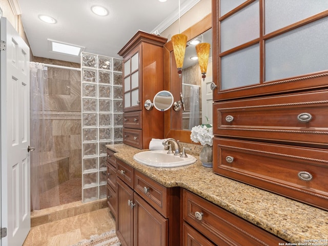 bathroom featuring vanity, ornamental molding, a tile shower, and a skylight