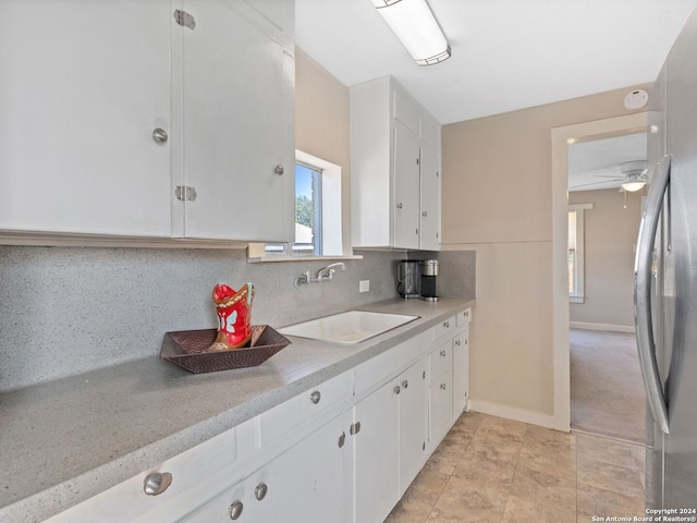 kitchen with sink, decorative backsplash, ceiling fan, white cabinets, and stainless steel refrigerator