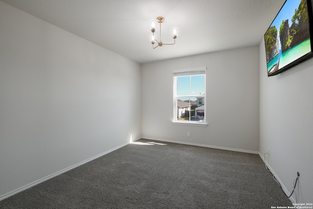 carpeted empty room with a notable chandelier