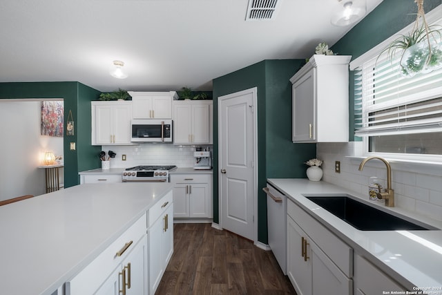 kitchen featuring decorative backsplash, dark hardwood / wood-style floors, sink, white cabinetry, and appliances with stainless steel finishes