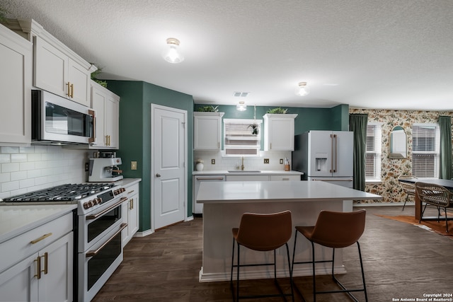 kitchen with sink, high quality appliances, white cabinetry, and a kitchen island