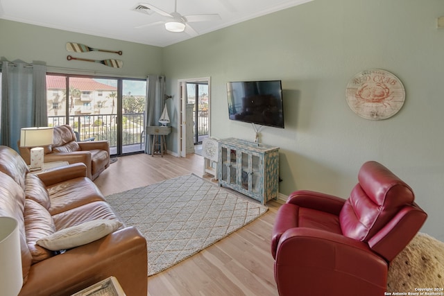 living room with light hardwood / wood-style floors, ornamental molding, and ceiling fan