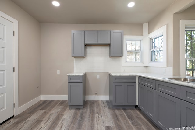 kitchen featuring dark wood-type flooring, decorative backsplash, sink, and gray cabinets