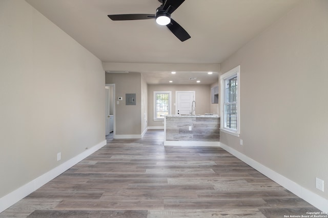 unfurnished living room with light hardwood / wood-style floors, sink, and ceiling fan