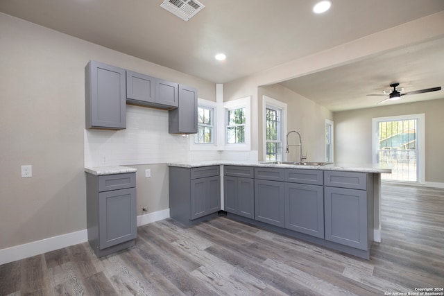 kitchen with gray cabinetry, wood-type flooring, sink, tasteful backsplash, and ceiling fan