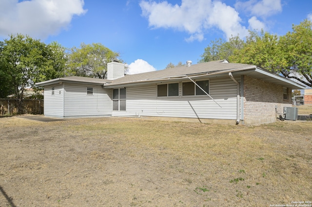 rear view of property featuring cooling unit and a yard