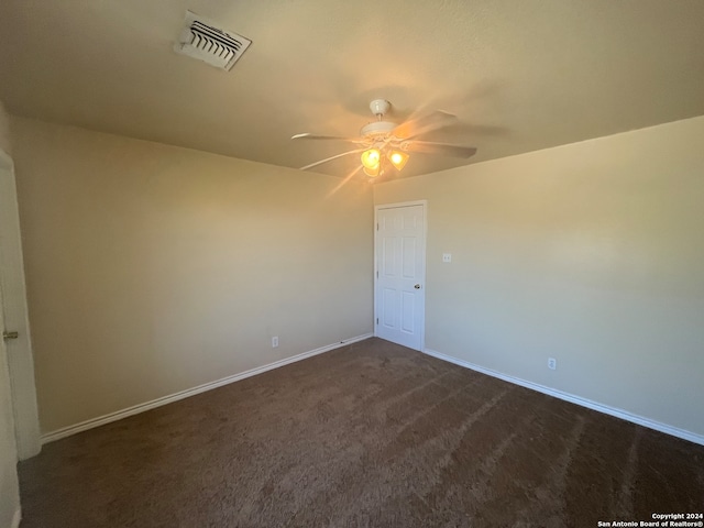 spare room featuring dark carpet and ceiling fan