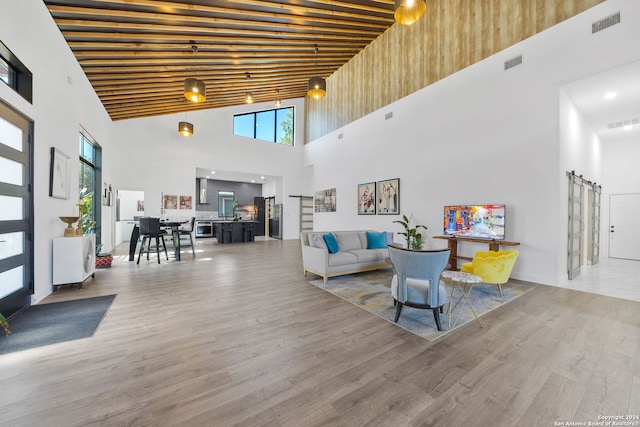 living room with hardwood / wood-style floors, a barn door, and high vaulted ceiling