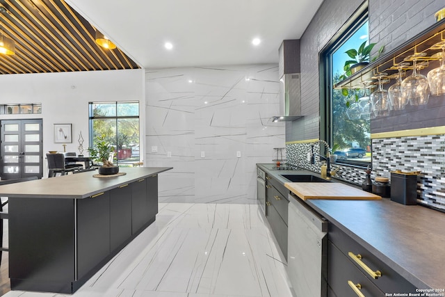 kitchen with tasteful backsplash, sink, a center island, tile walls, and stainless steel dishwasher