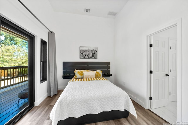 bedroom with lofted ceiling, access to exterior, and wood-type flooring