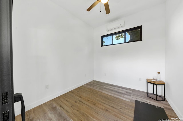 spare room with ceiling fan, wood-type flooring, and a wall unit AC