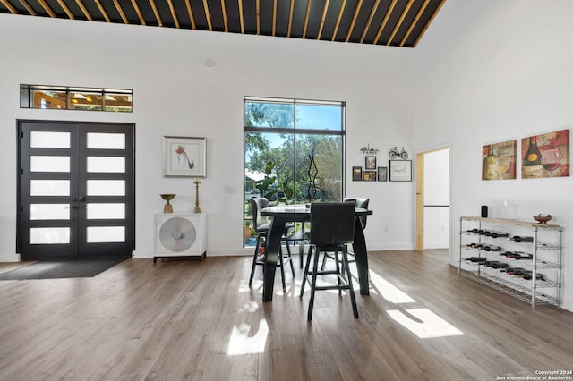 dining space featuring a towering ceiling, french doors, and wood-type flooring