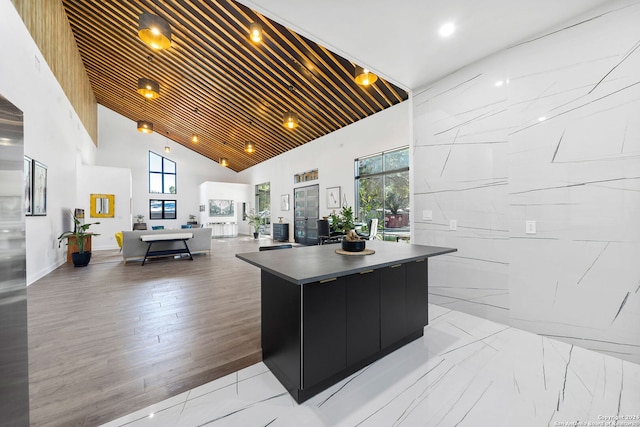 kitchen featuring a spacious island, wood ceiling, high vaulted ceiling, and a healthy amount of sunlight