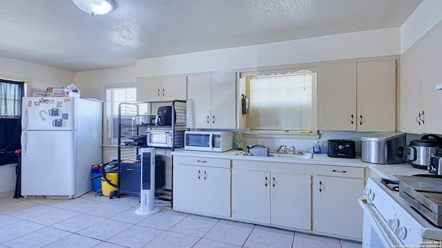 kitchen featuring white appliances, light tile patterned floors, white cabinetry, and sink