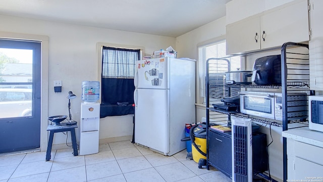 kitchen featuring white cabinets, light tile patterned flooring, and white refrigerator