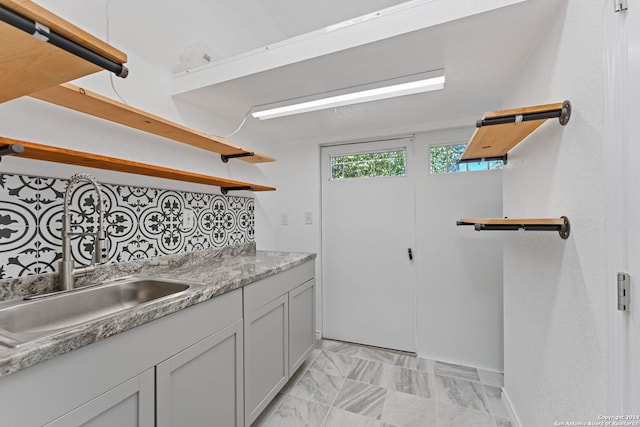 kitchen featuring decorative backsplash, light stone counters, and sink