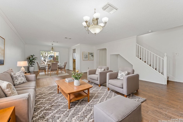 living room with wood-type flooring, a textured ceiling, ornamental molding, and a notable chandelier