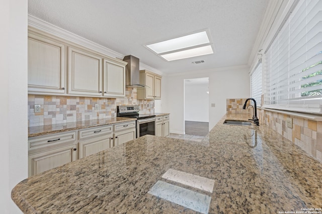 kitchen featuring cream cabinets, wall chimney range hood, crown molding, sink, and electric range