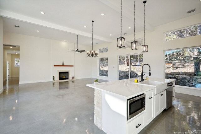 kitchen featuring visible vents, a fireplace with raised hearth, appliances with stainless steel finishes, a sink, and a wealth of natural light