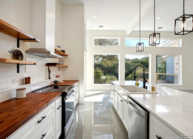 kitchen with butcher block countertops, decorative light fixtures, tasteful backsplash, sink, and stainless steel appliances