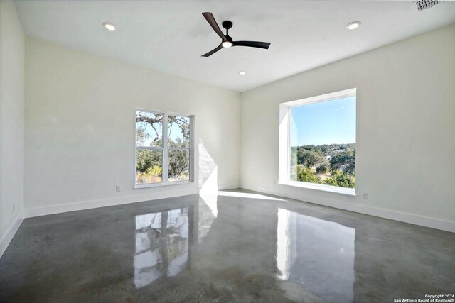 empty room with plenty of natural light, finished concrete floors, and baseboards