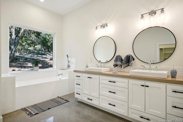 bathroom featuring concrete flooring, vanity, and a bath