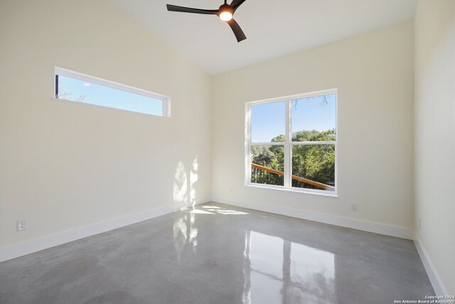 spare room featuring finished concrete floors, ceiling fan, and baseboards