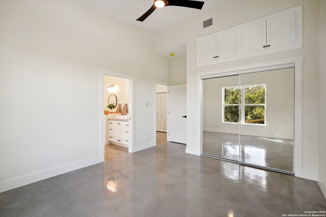 unfurnished bedroom with ensuite bathroom, ceiling fan, and a closet