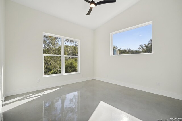 spare room featuring finished concrete flooring, baseboards, and a healthy amount of sunlight