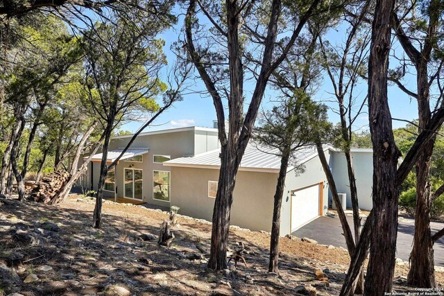 view of property exterior with a garage, a standing seam roof, metal roof, and stucco siding