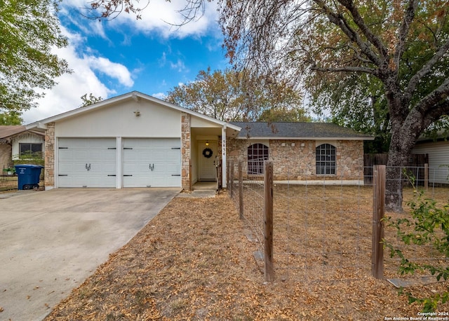ranch-style home featuring fence, driveway, stone siding, and a garage