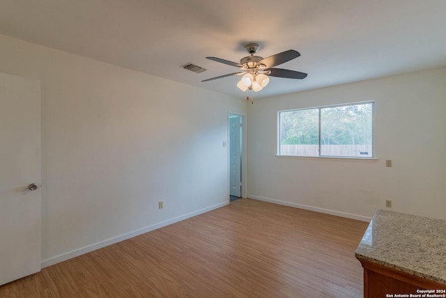 unfurnished room with a ceiling fan, baseboards, visible vents, and light wood-style floors