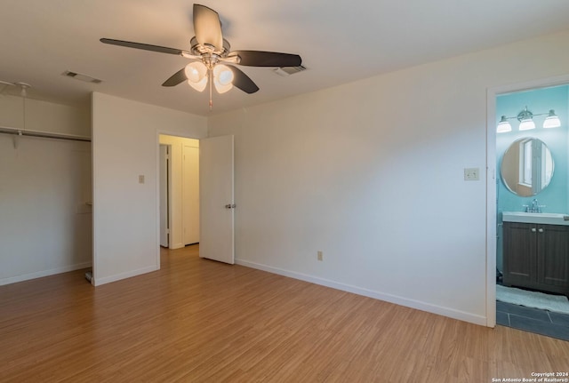 unfurnished bedroom featuring visible vents, a closet, light wood-style floors, baseboards, and a sink