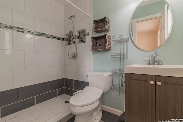 bathroom featuring vanity, a tile shower, and toilet