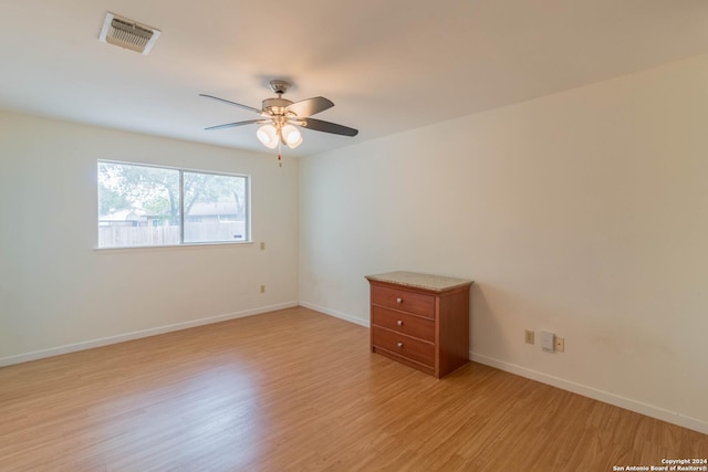 spare room featuring visible vents, light wood-style floors, ceiling fan, and baseboards