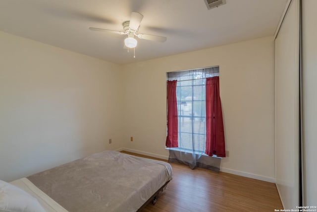 bedroom featuring baseboards, ceiling fan, wood finished floors, and visible vents