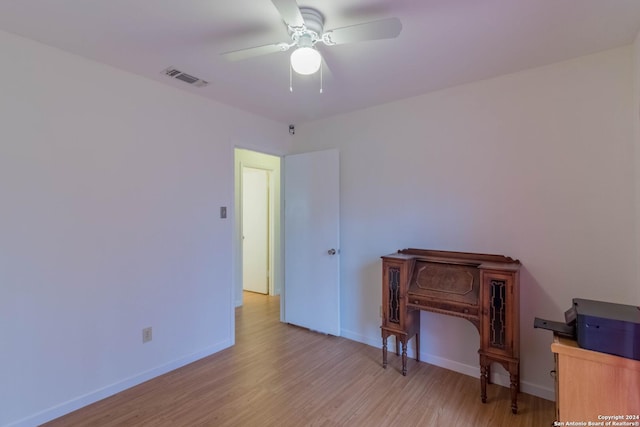 interior space featuring baseboards, visible vents, ceiling fan, and light wood finished floors
