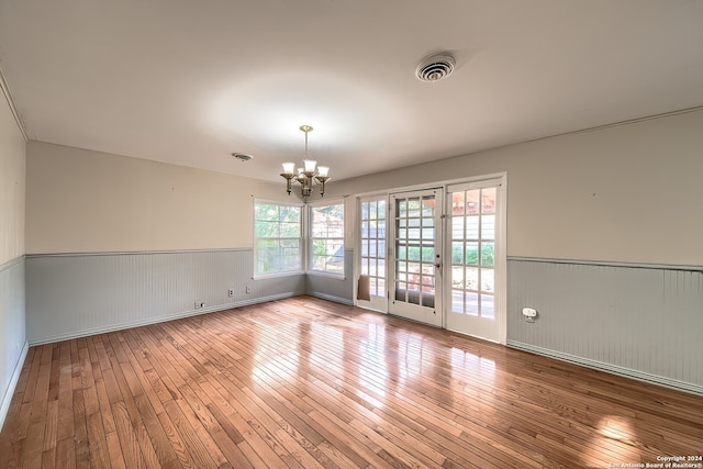 unfurnished room featuring a notable chandelier and light hardwood / wood-style floors