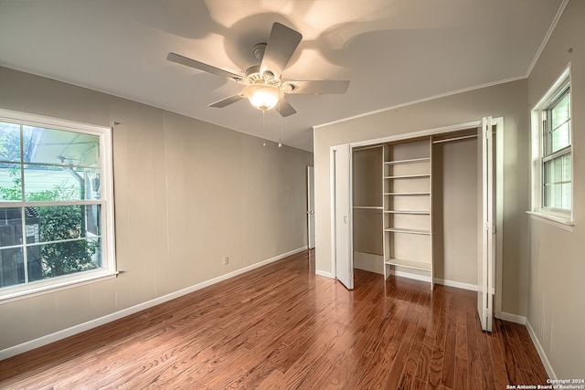 unfurnished bedroom with a closet, hardwood / wood-style flooring, multiple windows, and ceiling fan