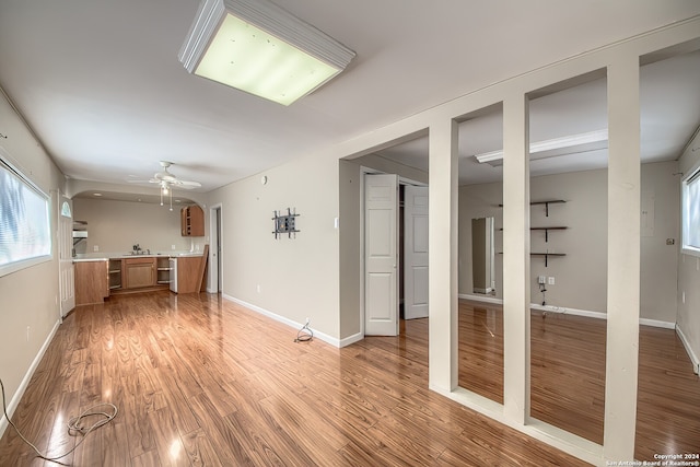 unfurnished living room with light hardwood / wood-style flooring, ceiling fan, and sink