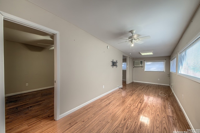 unfurnished bedroom with a wall unit AC, a closet, ceiling fan, and hardwood / wood-style floors