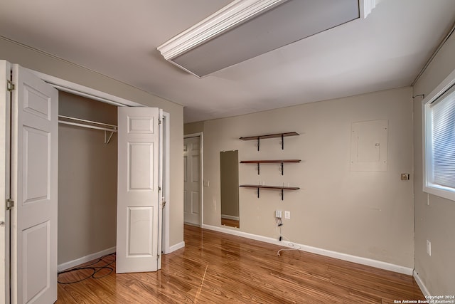 unfurnished bedroom with electric panel, light hardwood / wood-style flooring, and a closet