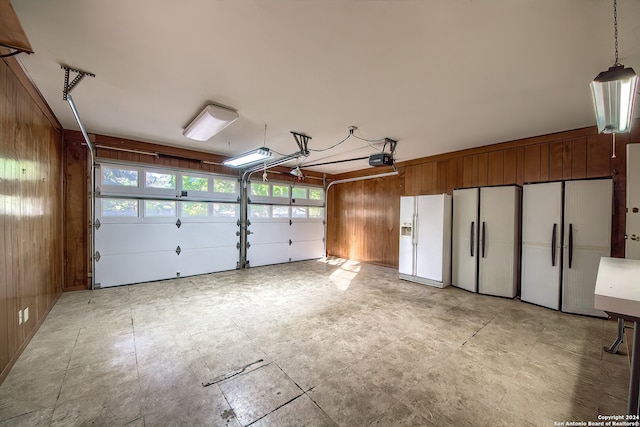 garage with white refrigerator, white fridge with ice dispenser, and wood walls